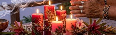 Ritual de amor místico con velas rojas decoradas con motivos de la selva y humo de incienso, realizado por manos con anillos y pulseras tradicionales a orillas del Río Amazonas cerca de Leticia y Tabatinga